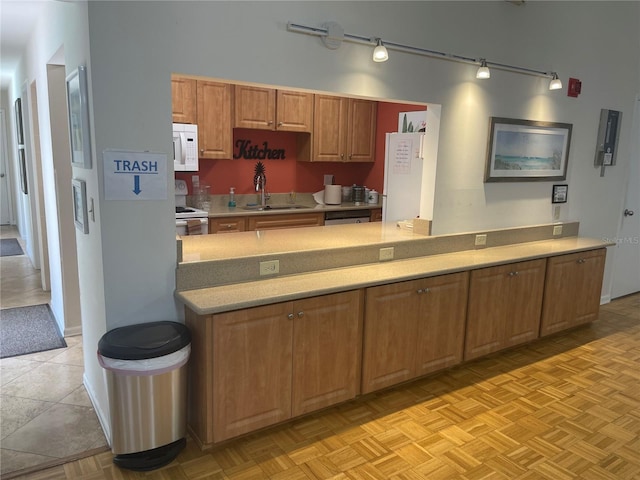 kitchen with sink, white appliances, and light parquet flooring