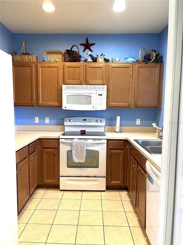 kitchen with sink, light tile patterned floors, and white appliances