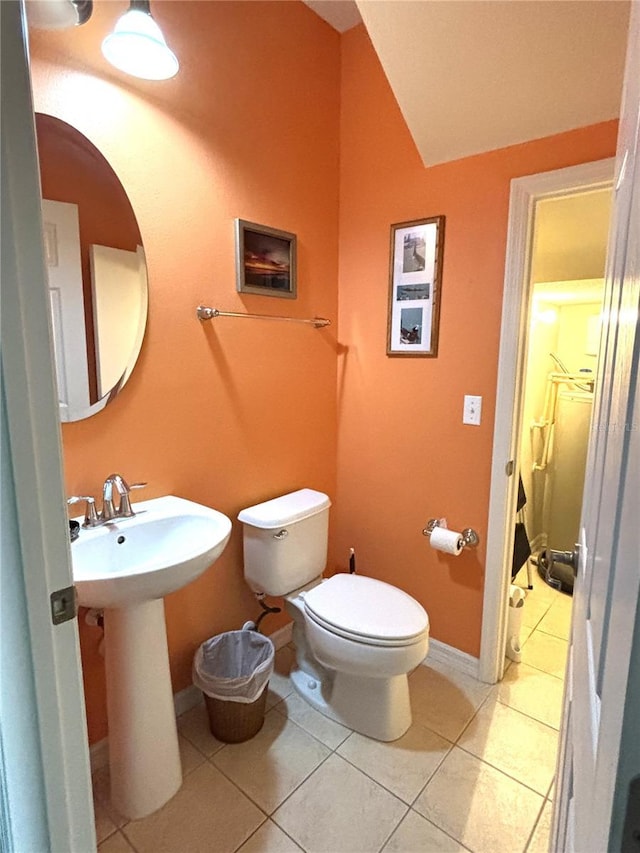 bathroom with tile patterned flooring, vaulted ceiling, sink, and toilet