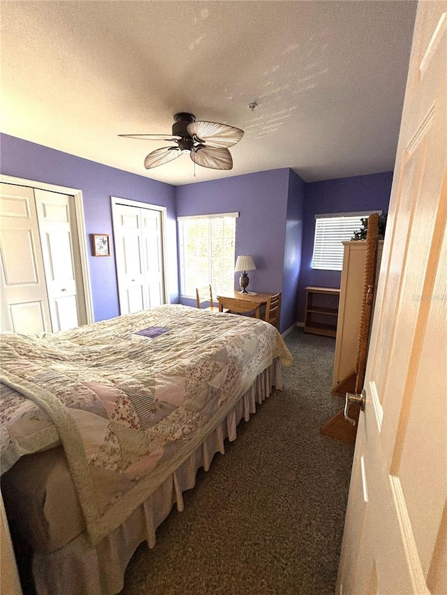 carpeted bedroom featuring ceiling fan, two closets, and a textured ceiling