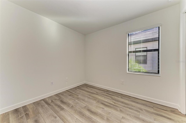 empty room featuring baseboards and light wood finished floors