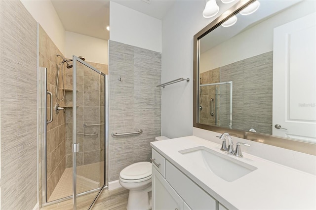 bathroom with a stall shower, vanity, and toilet