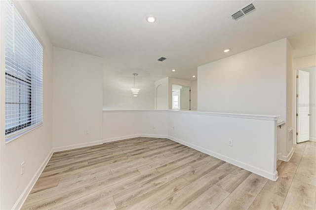 empty room with light wood finished floors, baseboards, visible vents, and recessed lighting