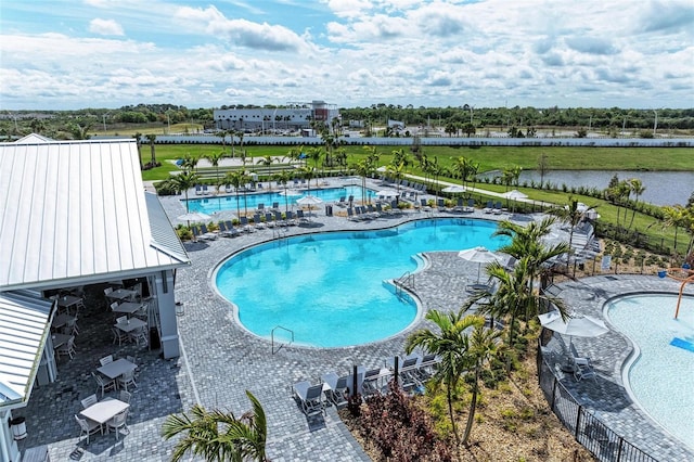 community pool featuring a patio area, a water view, and fence