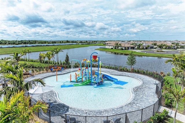 view of swimming pool with playground community, a water view, and fence