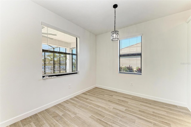 spare room with light wood-style floors, a healthy amount of sunlight, and baseboards