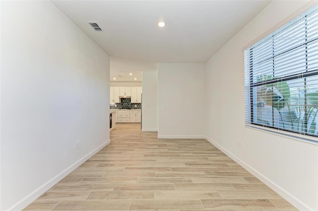 spare room featuring light wood-type flooring, visible vents, baseboards, and recessed lighting