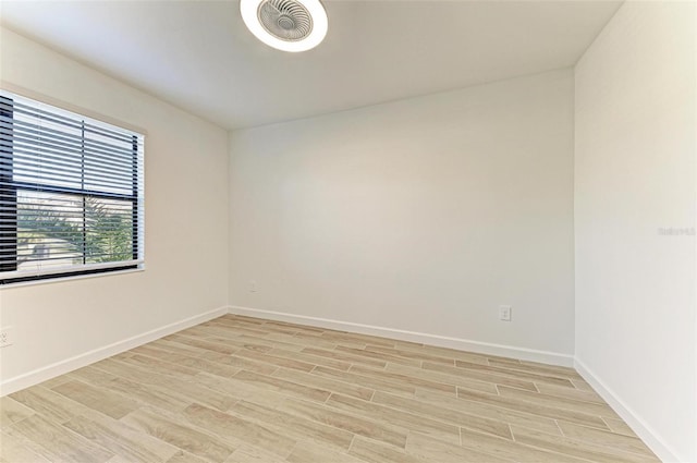 empty room featuring light wood-type flooring, visible vents, and baseboards