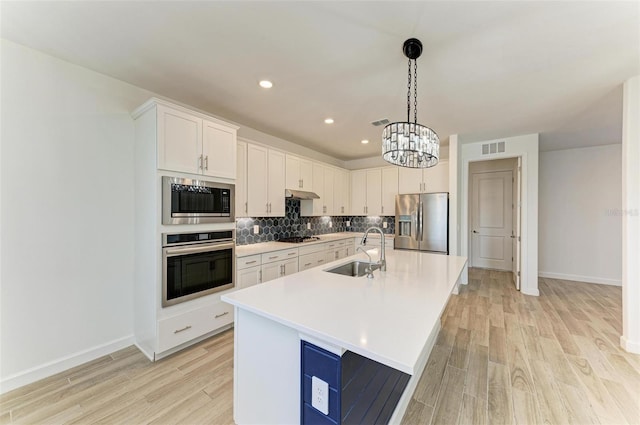 kitchen featuring stainless steel appliances, light countertops, visible vents, white cabinetry, and a sink