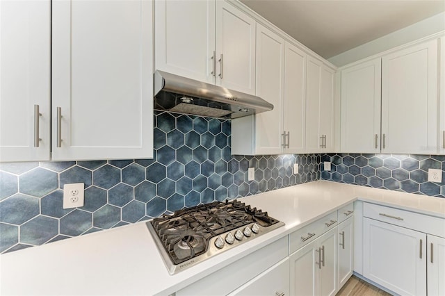 kitchen with stainless steel gas cooktop, under cabinet range hood, light countertops, and white cabinets