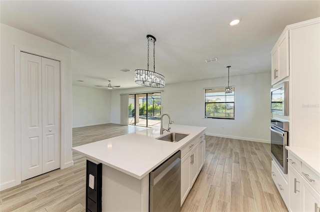 kitchen featuring a center island with sink, light countertops, appliances with stainless steel finishes, white cabinets, and a sink