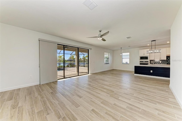 unfurnished living room with light wood finished floors, recessed lighting, visible vents, a ceiling fan, and baseboards