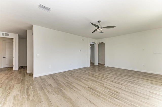 empty room featuring light wood-style flooring, visible vents, arched walkways, and a ceiling fan