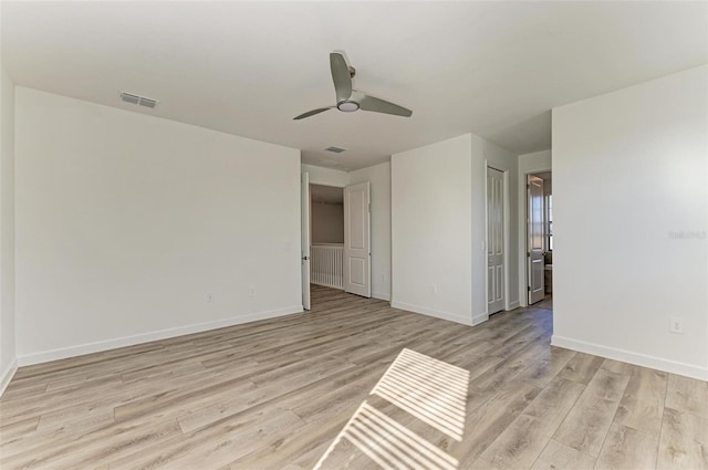 spare room featuring a ceiling fan, light wood-type flooring, visible vents, and baseboards