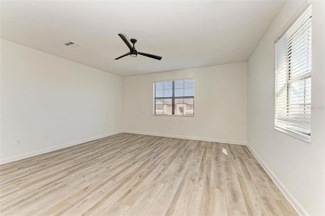 empty room with light wood-type flooring, visible vents, and a wealth of natural light