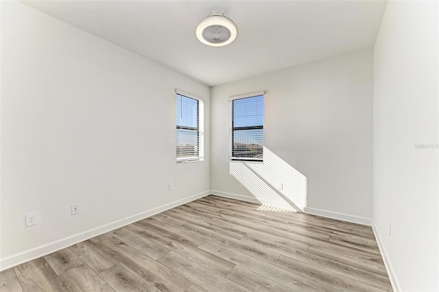 empty room featuring light wood finished floors and baseboards