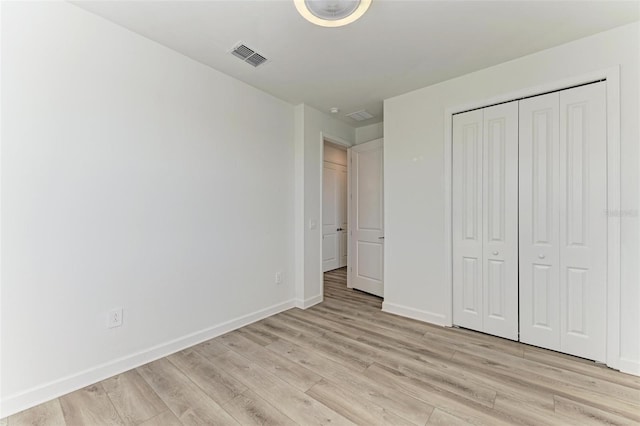 unfurnished bedroom featuring a closet, light wood-type flooring, visible vents, and baseboards