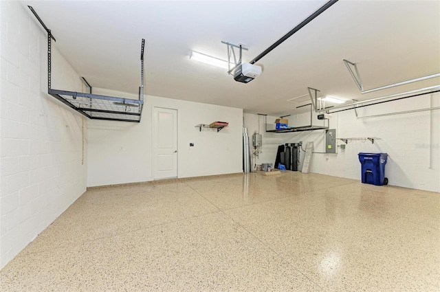 garage featuring concrete block wall, electric panel, and a garage door opener