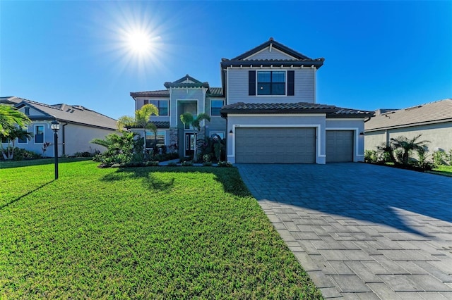 view of front of house featuring decorative driveway, a tile roof, stucco siding, an attached garage, and a front lawn