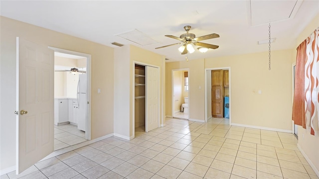 unfurnished bedroom with ceiling fan, light tile patterned floors, ensuite bath, and a closet