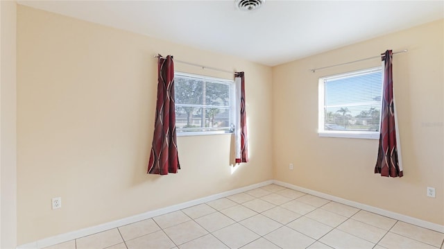 empty room with light tile patterned floors and a healthy amount of sunlight