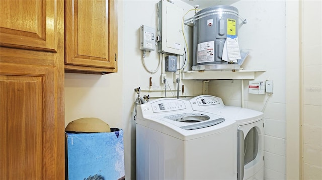 washroom featuring water heater, washer and clothes dryer, and cabinets