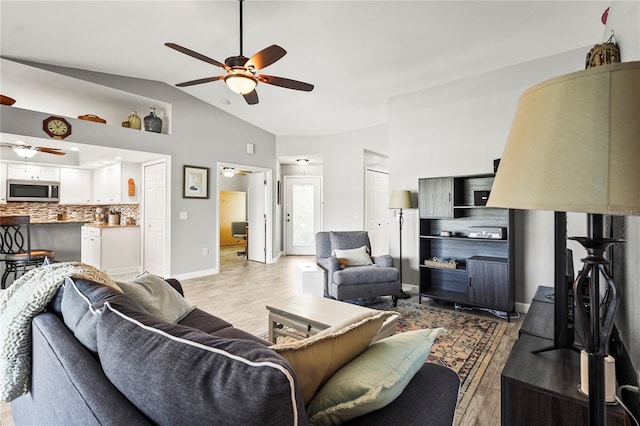 living room with vaulted ceiling, ceiling fan, and light wood-type flooring