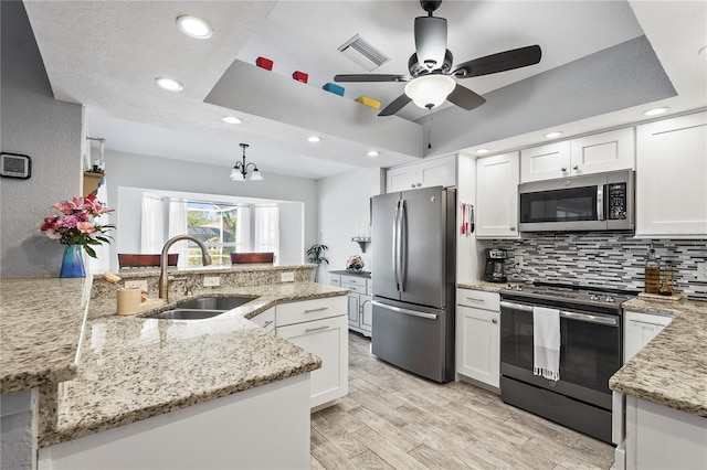 kitchen with stainless steel appliances, white cabinetry, sink, and a tray ceiling