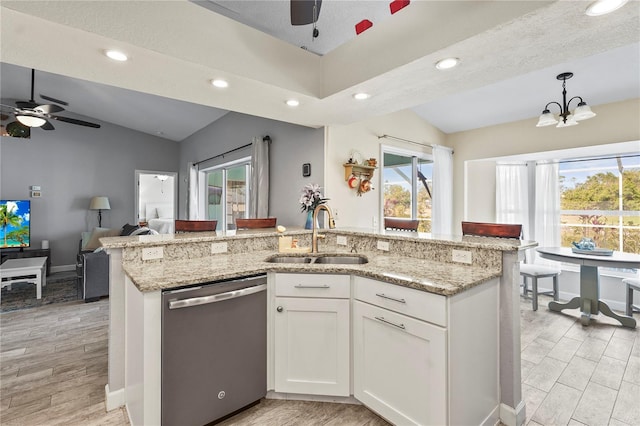 kitchen with lofted ceiling, sink, white cabinetry, decorative light fixtures, and stainless steel dishwasher