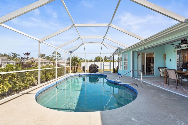 view of swimming pool with a patio, ceiling fan, and glass enclosure