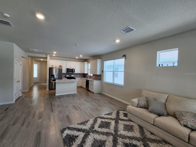 living room with a textured ceiling and light hardwood / wood-style floors