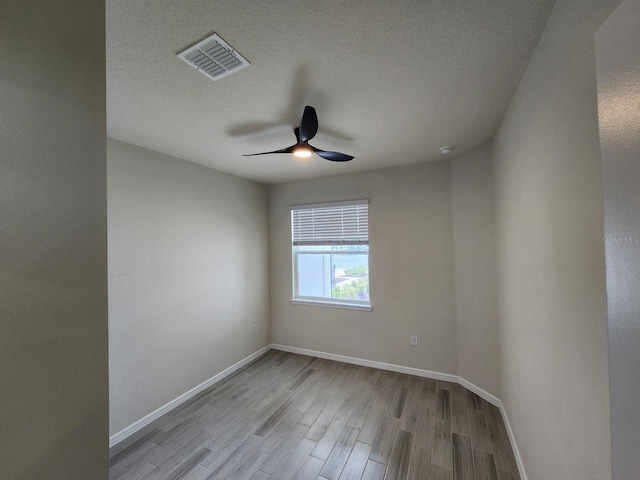 spare room with a textured ceiling, ceiling fan, and light wood-type flooring