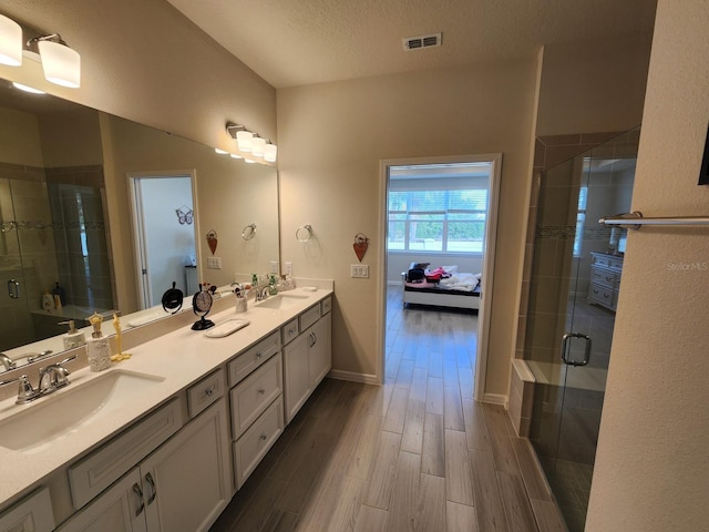 bathroom with vanity, hardwood / wood-style floors, an enclosed shower, and a textured ceiling