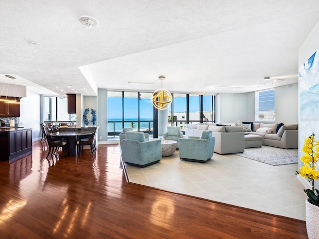 living room with a textured ceiling, wood-type flooring, a wall of windows, and a water view