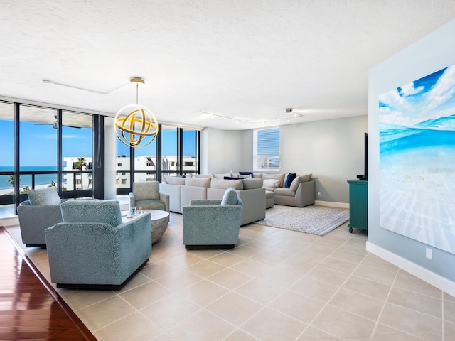 living room featuring a water view, track lighting, a textured ceiling, and light tile patterned floors