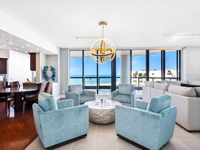 tiled living room featuring floor to ceiling windows, rail lighting, a textured ceiling, and a notable chandelier