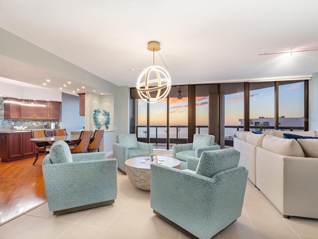 tiled living room with a healthy amount of sunlight, floor to ceiling windows, a chandelier, and a water view