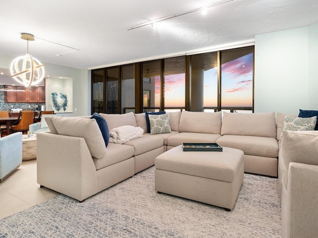 living room with expansive windows, rail lighting, light tile patterned floors, and a chandelier