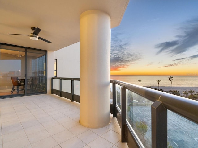 balcony at dusk with a water view and ceiling fan