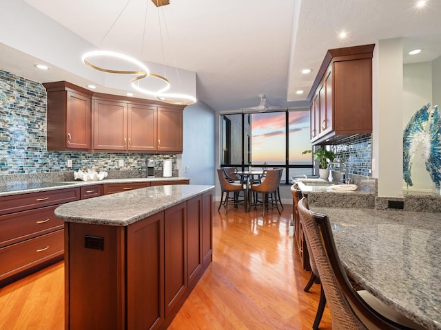 kitchen featuring hanging light fixtures, backsplash, light stone countertops, and a kitchen island