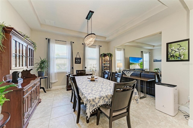 dining space with light tile patterned floors and a tray ceiling