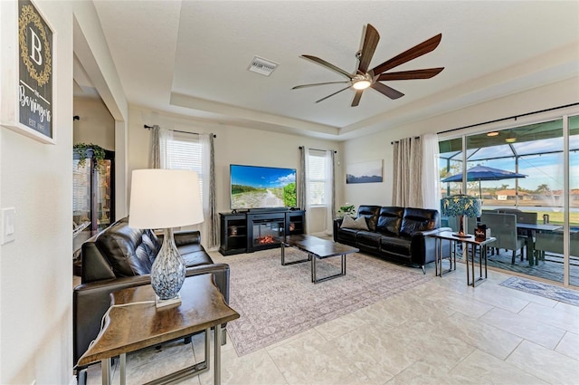 living room featuring ceiling fan and a tray ceiling