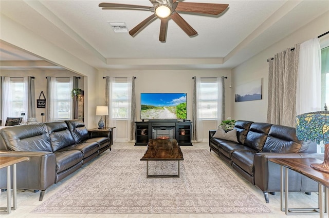 living room with plenty of natural light, a raised ceiling, and ceiling fan