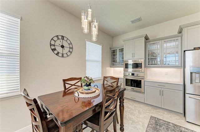 kitchen with stainless steel appliances, hanging light fixtures, gray cabinets, and backsplash