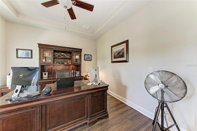 home office featuring dark hardwood / wood-style floors, ceiling fan, and a tray ceiling