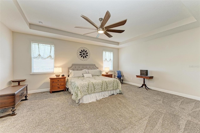 carpeted bedroom featuring ceiling fan and a tray ceiling