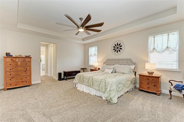 bedroom with a raised ceiling, ceiling fan, and carpet flooring