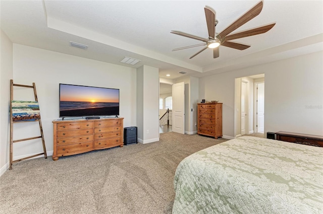 bedroom featuring light carpet, a tray ceiling, and ceiling fan