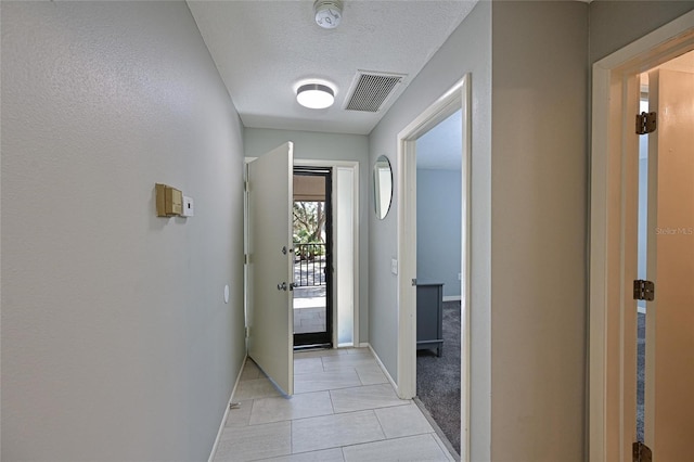 hallway with light tile patterned floors and a textured ceiling