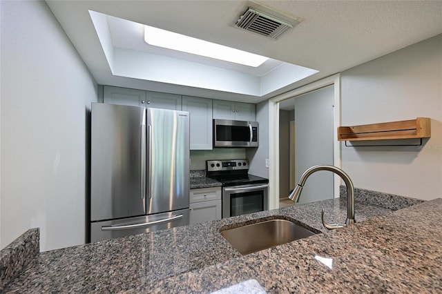 kitchen with sink, dark stone counters, and appliances with stainless steel finishes